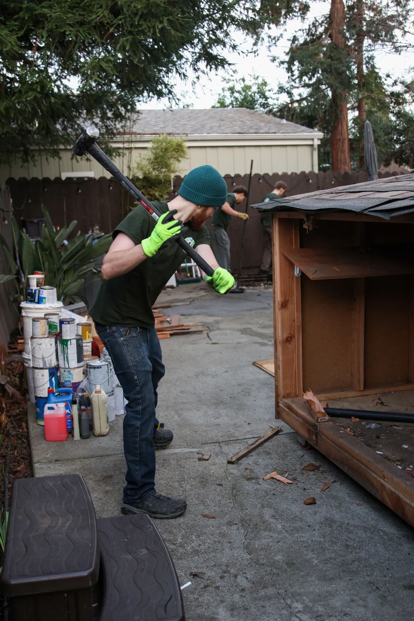 A Sullivan's Hauling crew member swinging a sledgehammer during a backyard shed tear-out