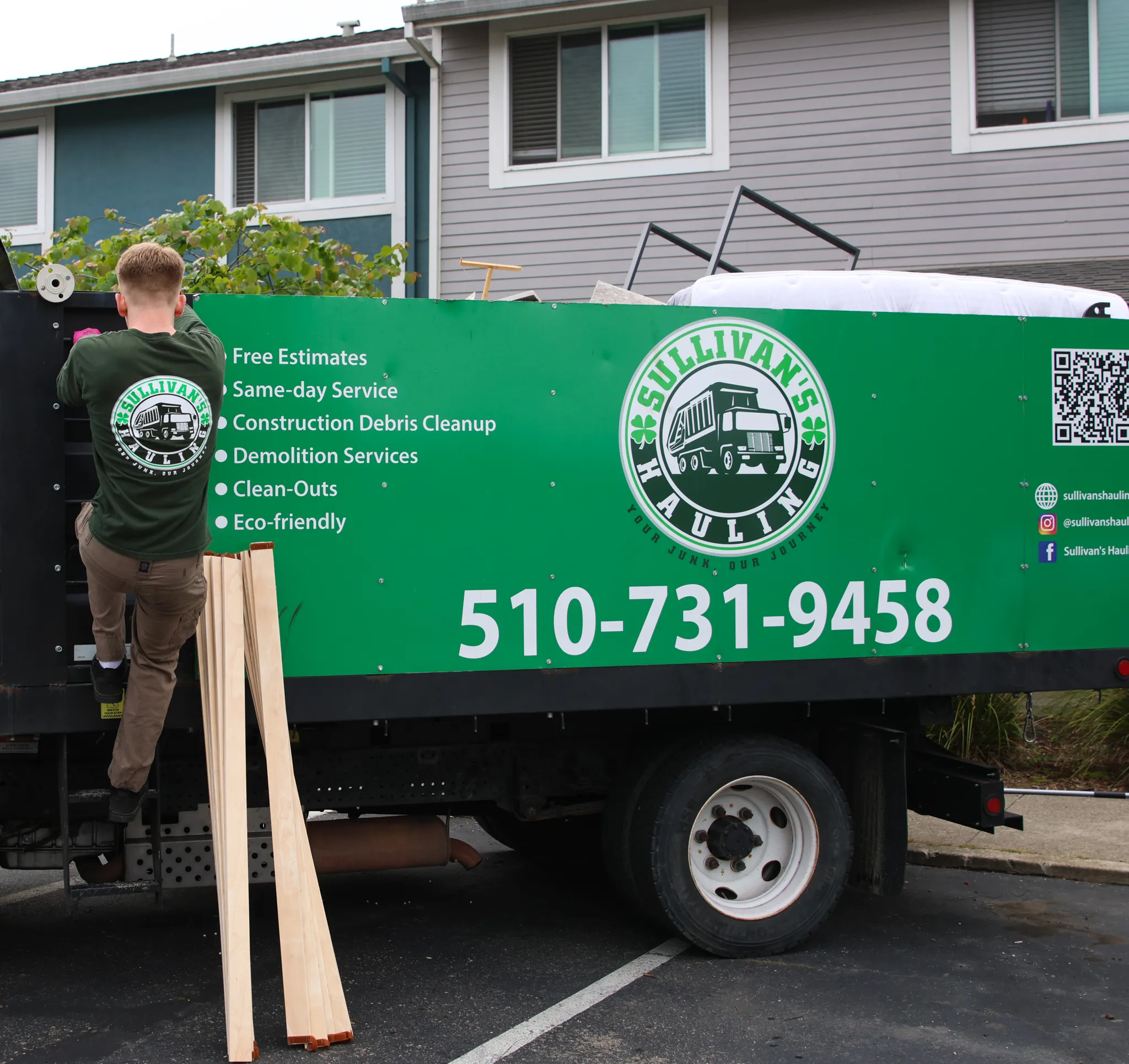 The side of the Sullivan's Hauling truck, loaded above the rails, showing the company seal and phone number