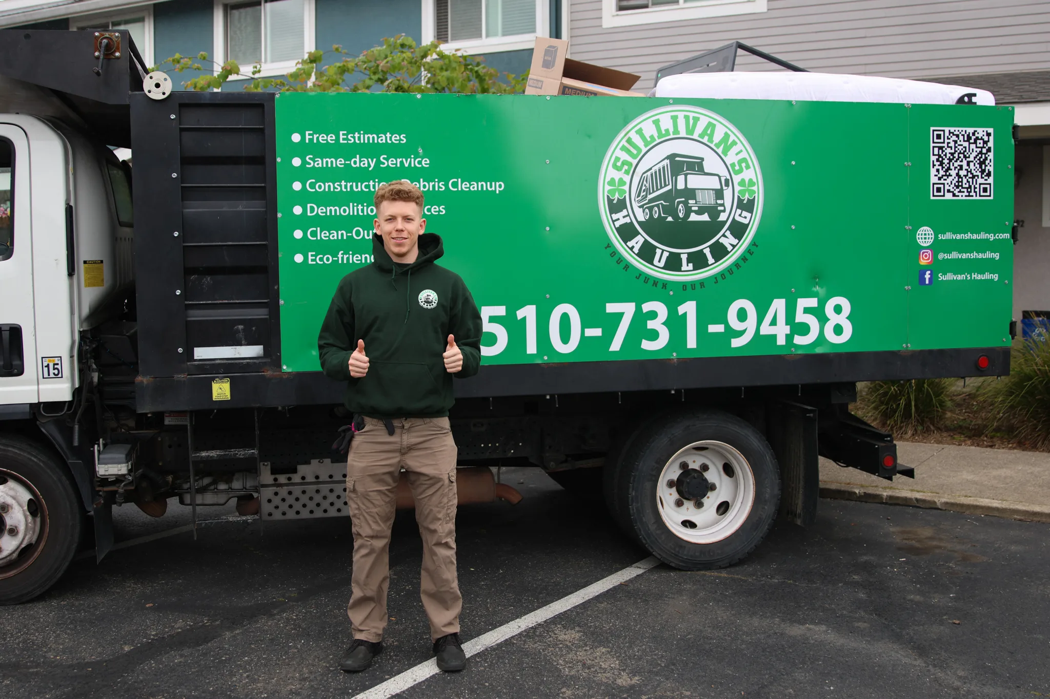 A Sullivan's Hauling crew member standing in front of the branded green dump truck